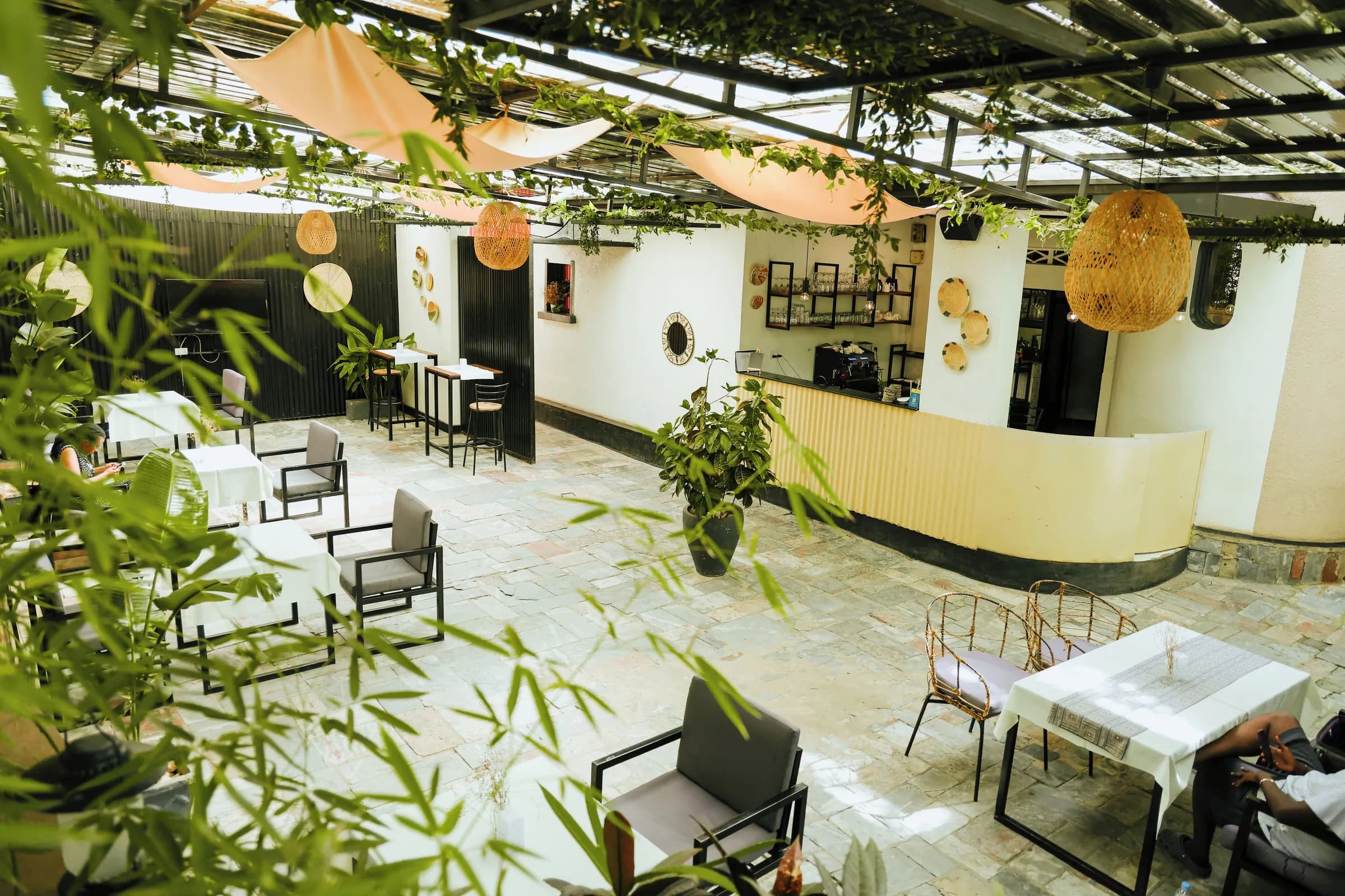 The courtyard at Kalih Villa in the late morning, wicker lanterns strung above white tables and planted beds