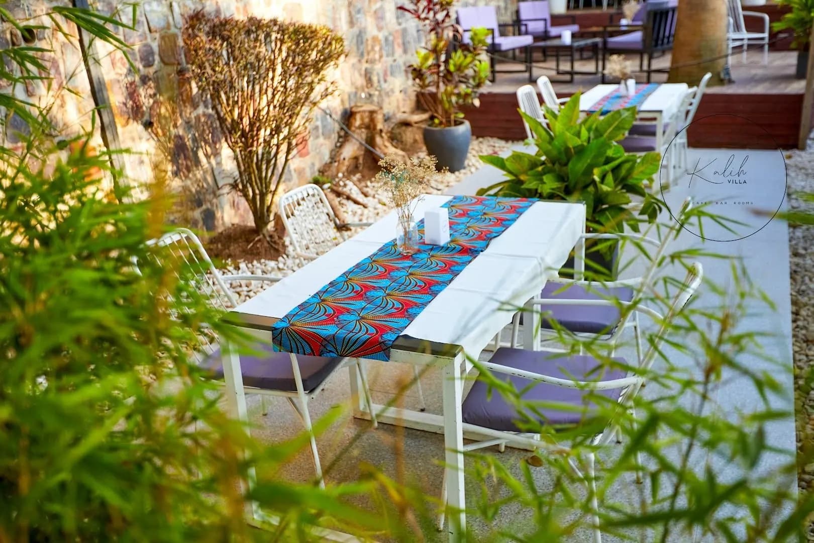 A long table at Kalih Villa dressed with a red and blue kitenge runner, white chairs on either side