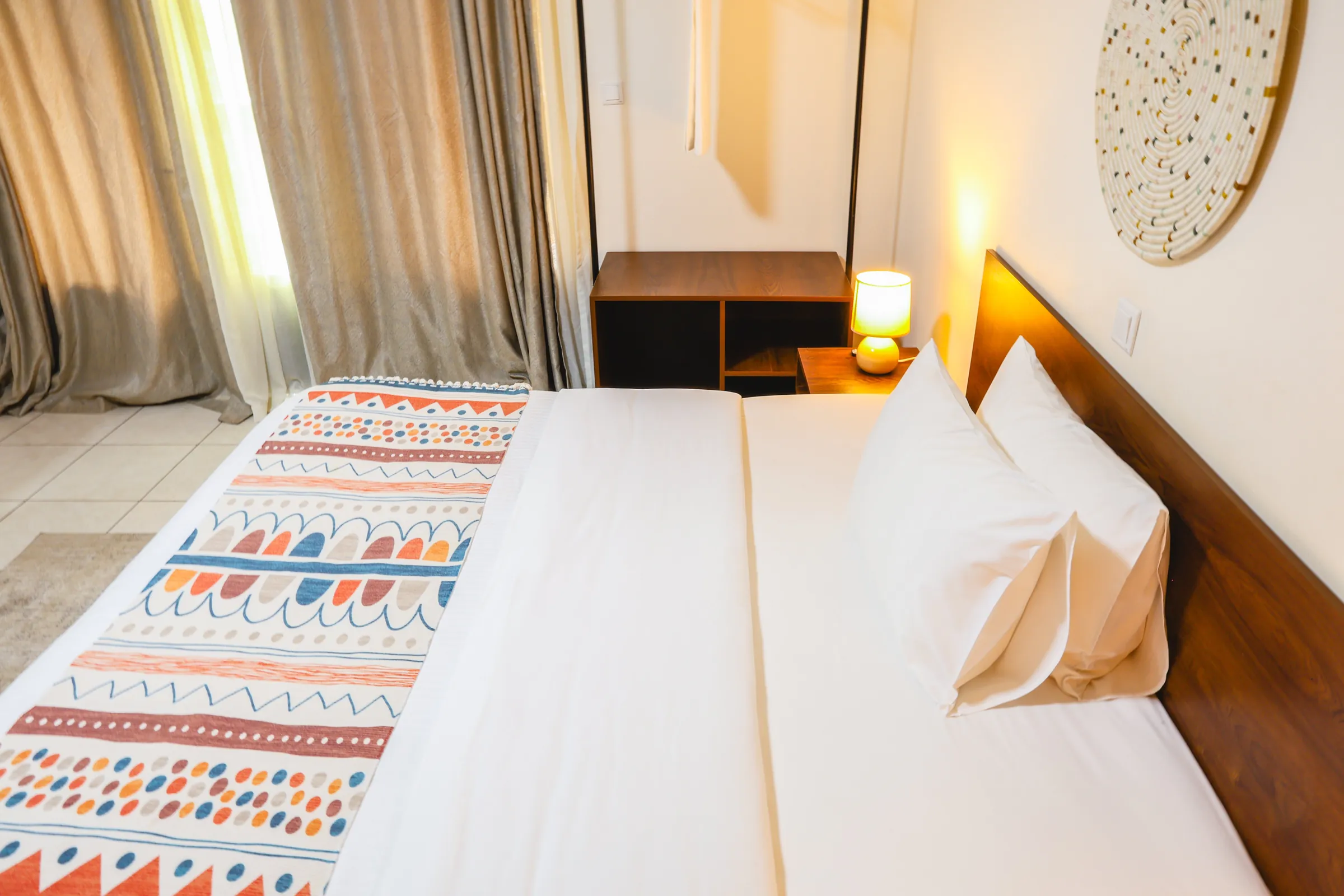 A room at Kalih Villa, white bed dressed with a patterned runner and a warm bedside lamp