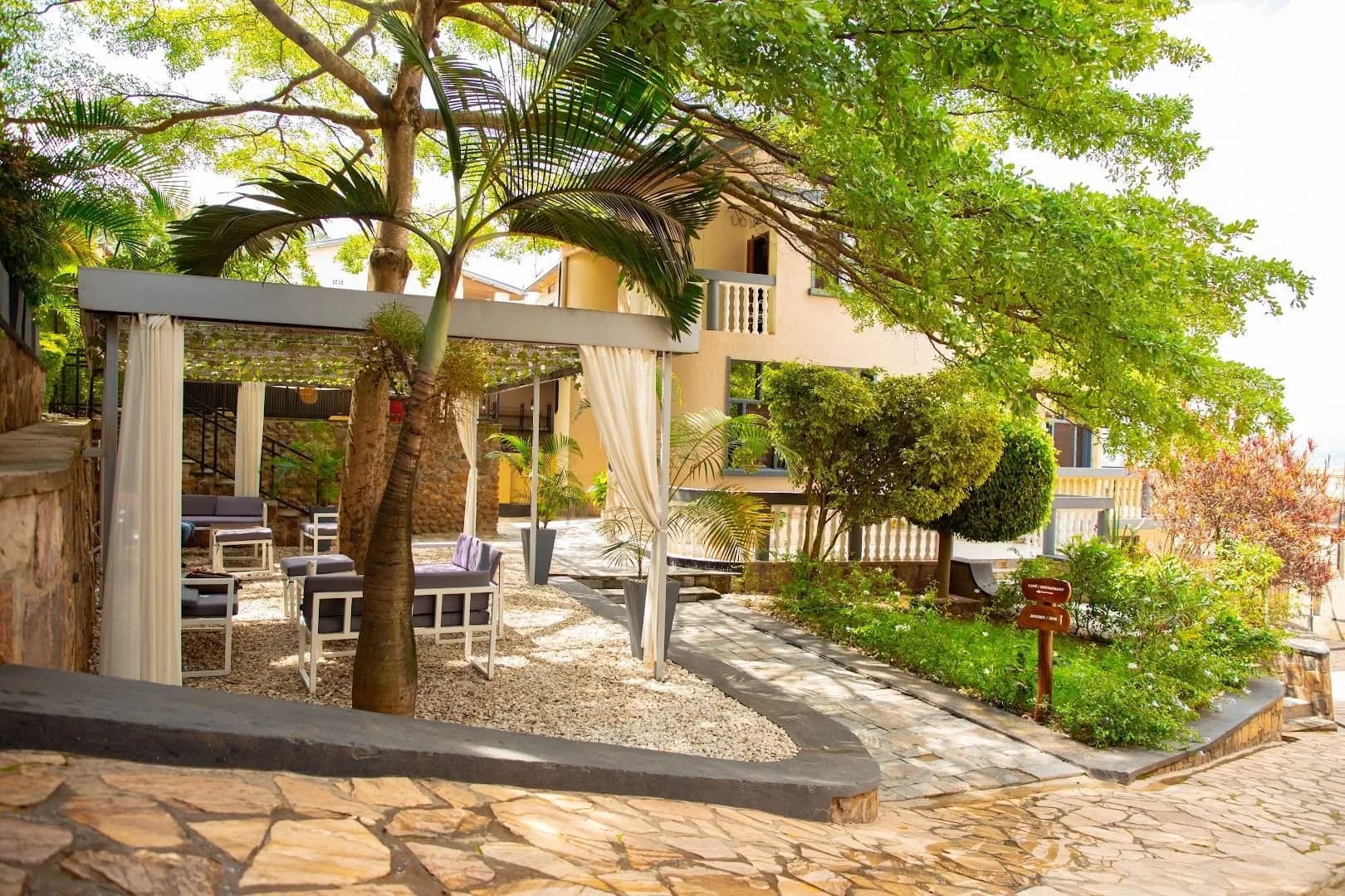 The walk into Kalih Villa: a flagstone path under trees, past a pergola hung with pale curtains