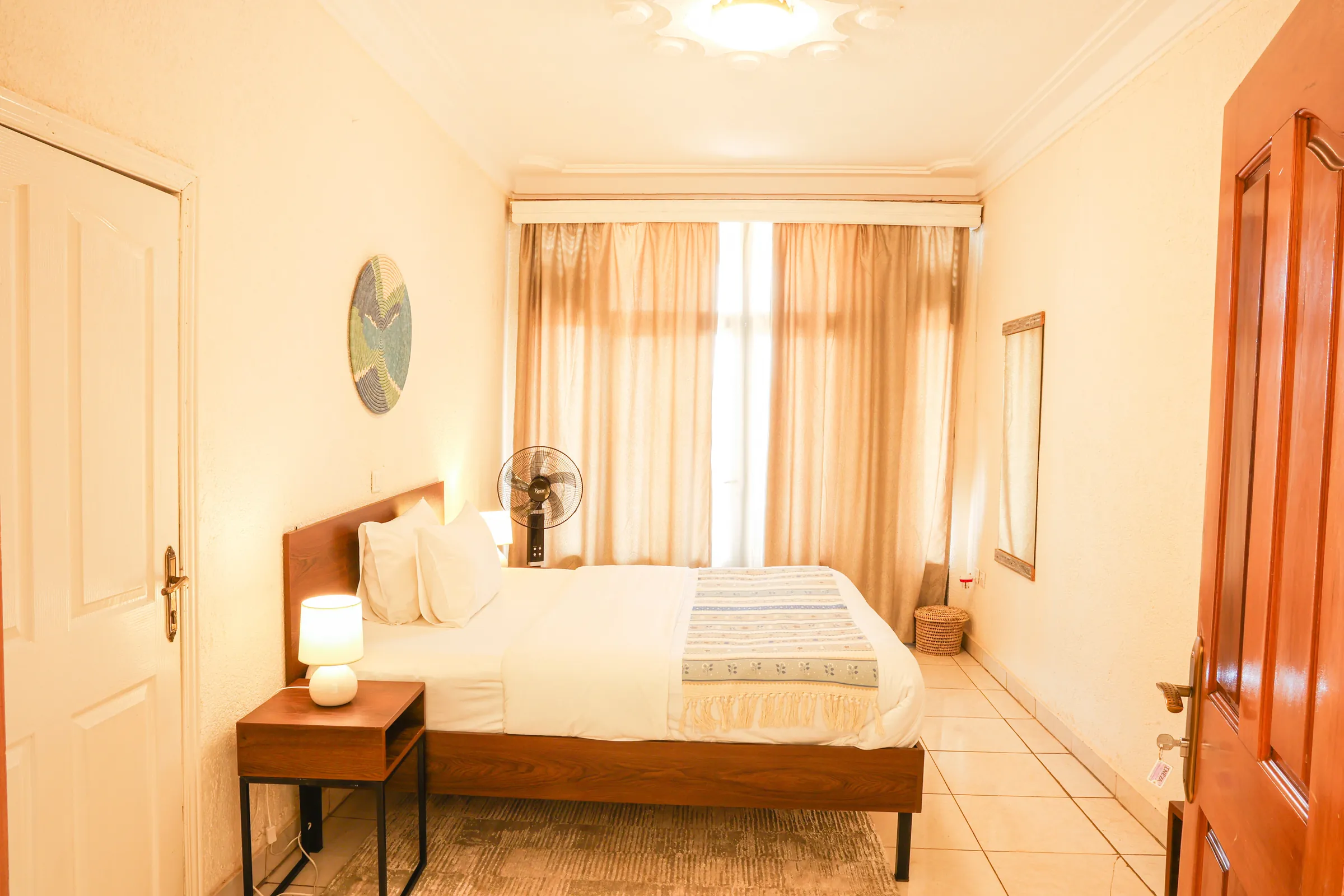 A room at Kalih Villa: a made bed, warm lamplight and a curtained window